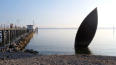 Bootsanlegestelle in Hagnau. Im Vordergrund eine Bootskulptur als Erinnerung an die Seegfrörne vor 55 Jahren. Damals war der Bodensee komplett zugefroren.